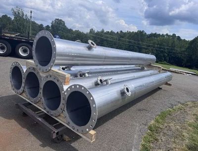 Fabricated exhaust silencers with flanged ends, staged outdoors before shipment