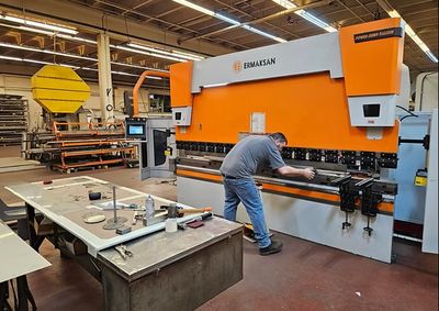 An operator forming sheet metal on a CNC press brake